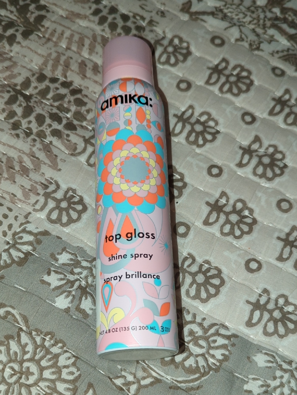 amika Top Gloss Shine Spray – Pastel Pink Bottle with Multicolor Floral Pattern